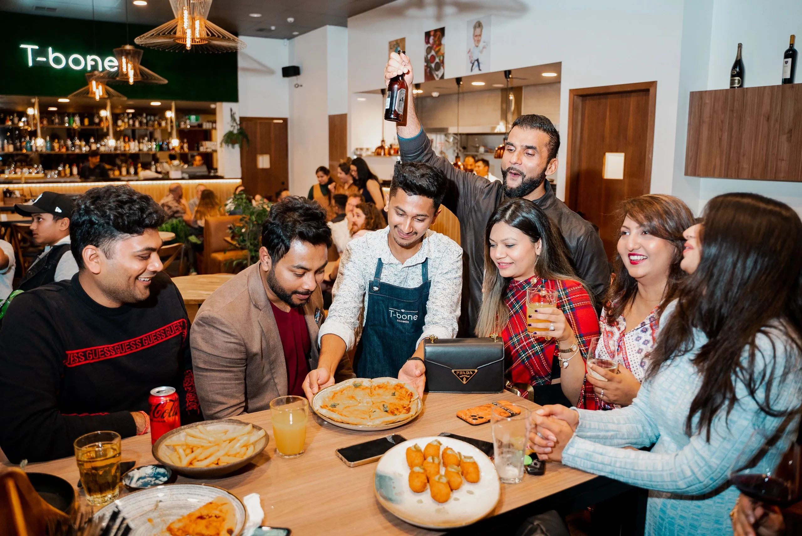 A table of friends laughing over drinks and share plates at T-bone
